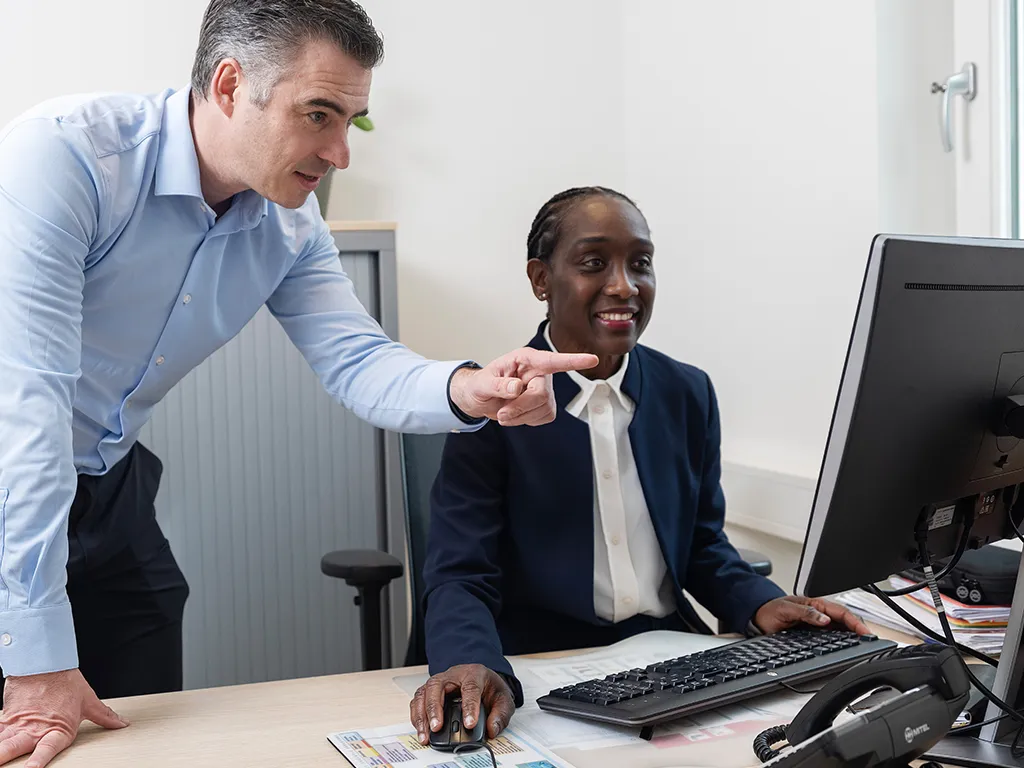 Man en vrouw kijken naar computer achter bureau